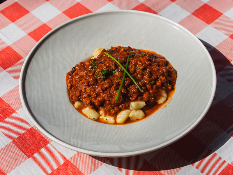 Ñoquis de sémola gratinados con bolognesa en Caudillo Bar, Saavedra